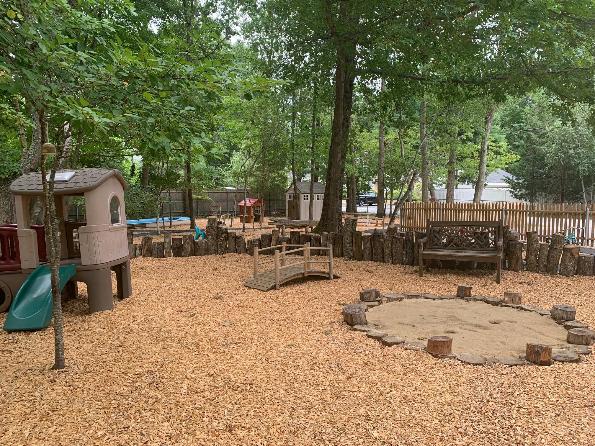 Outdoor playground with playhouse, bridge, and sandbox