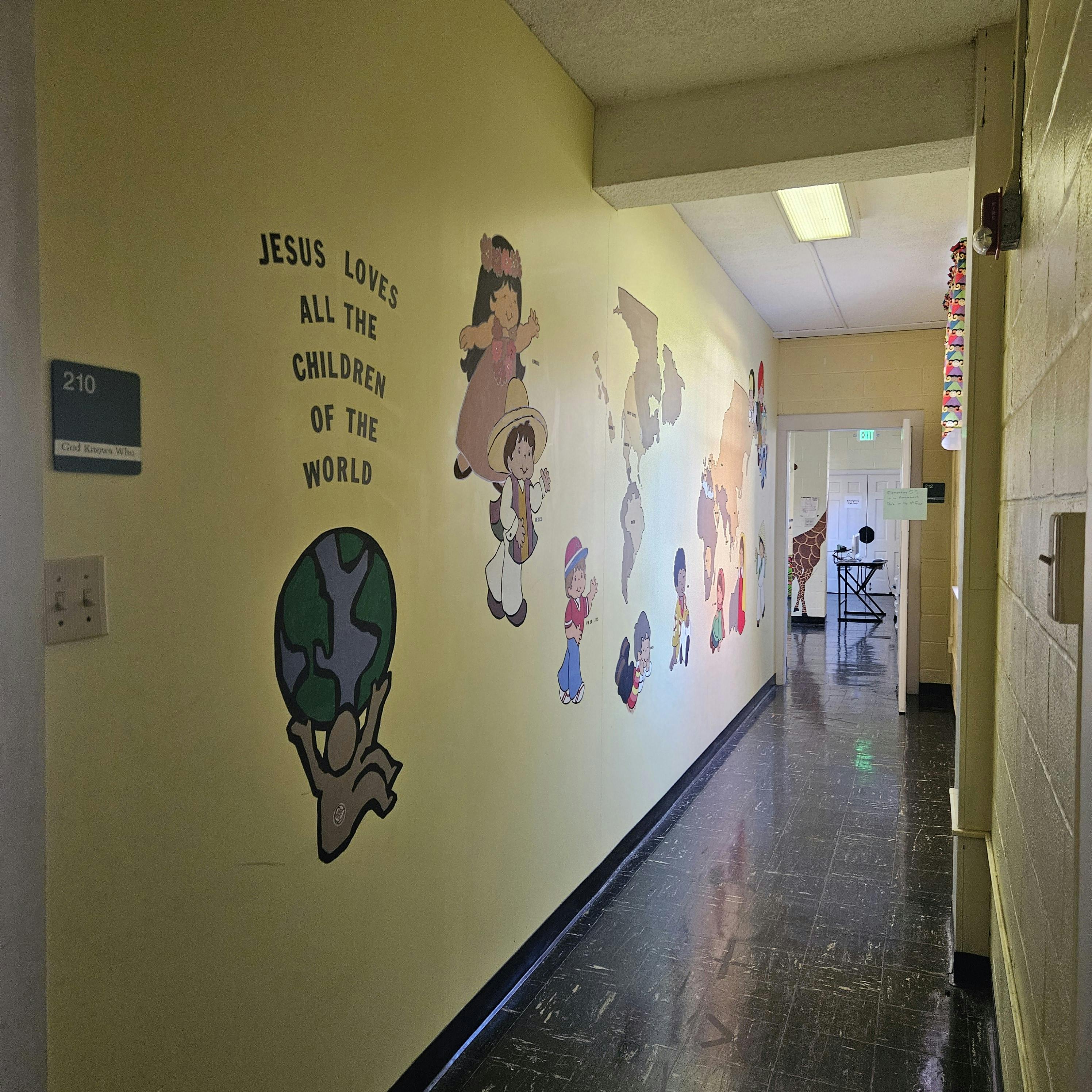 Hallway with wall art of children and world map, text "Jesus loves all the children of the world"
