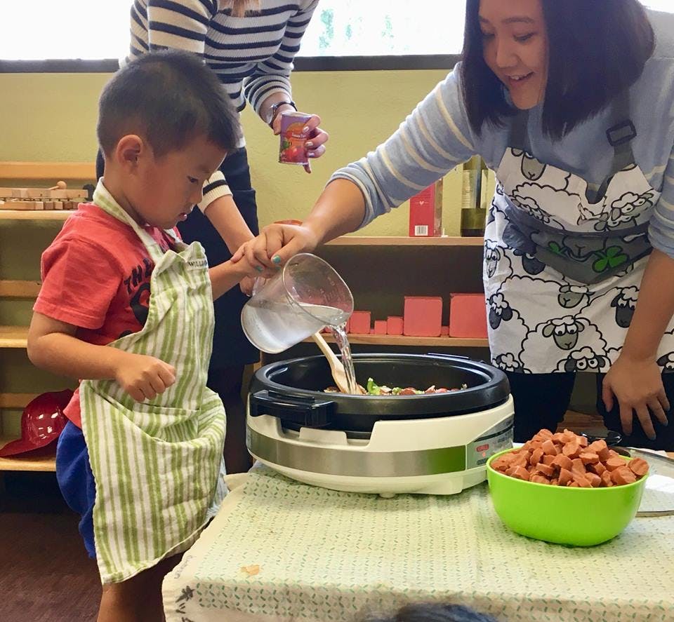 Adult and child pouring liquid from a measuring cup into a cooking pot