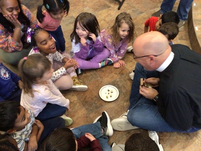 Adult and children sitting in a circle looking at a plate on a plate