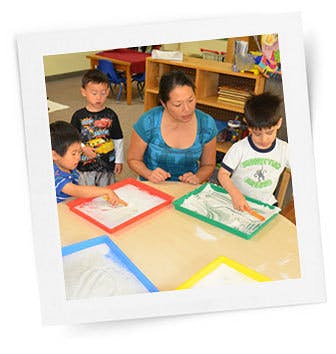 Adult and three children at a table with trays