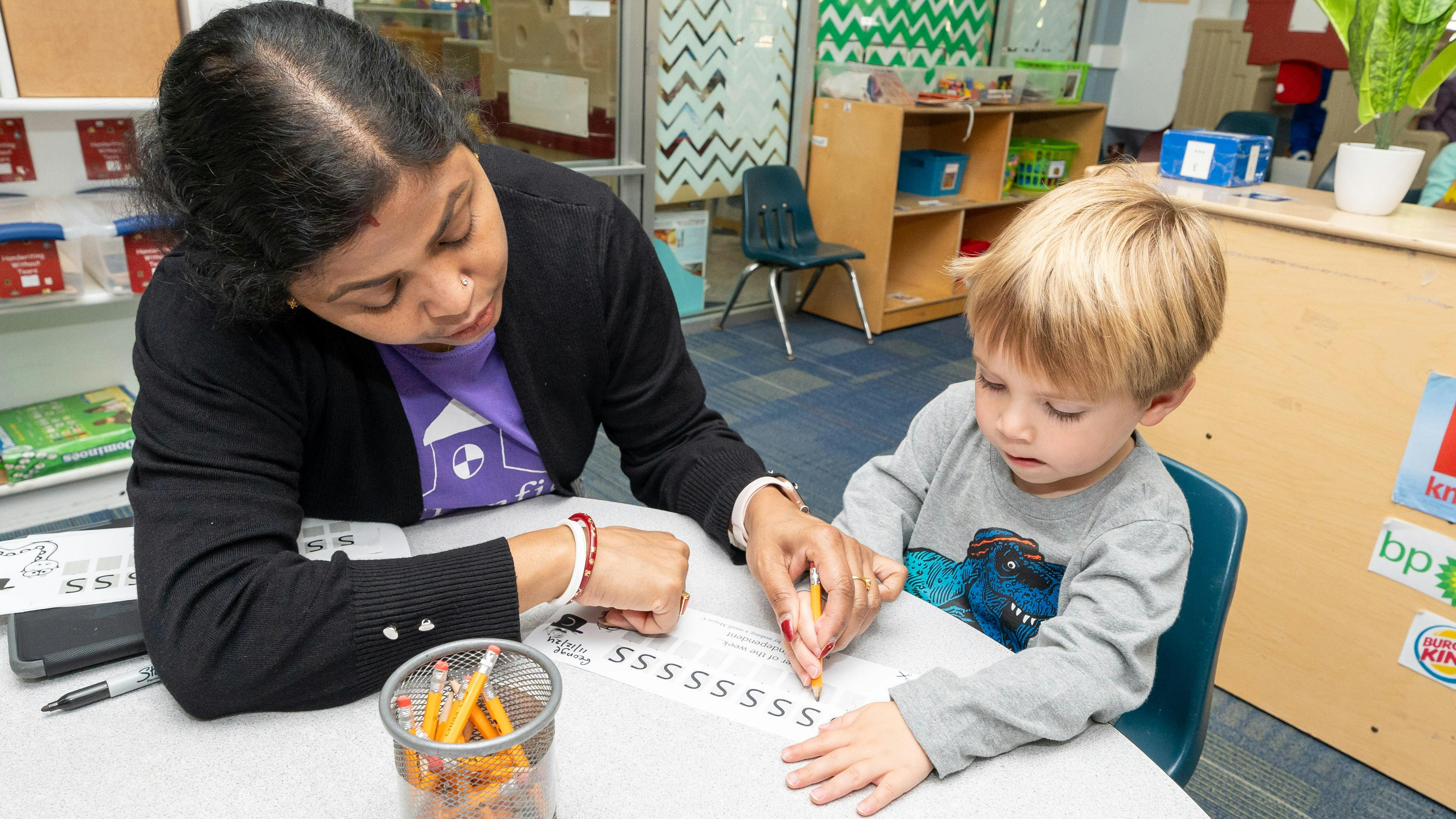 Person and child writing at a table