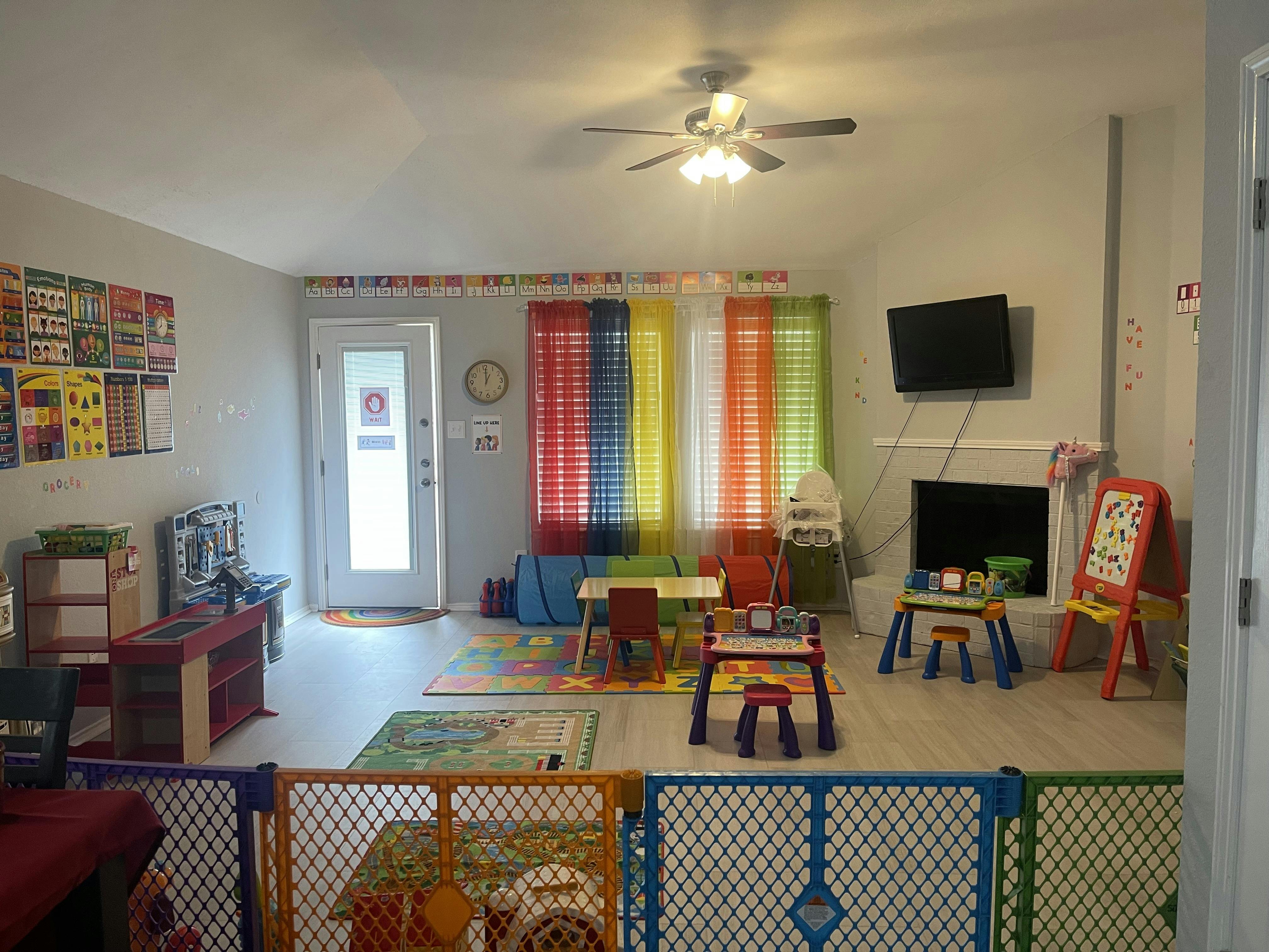 Playroom with colorful blinds, small tables, and a playpen