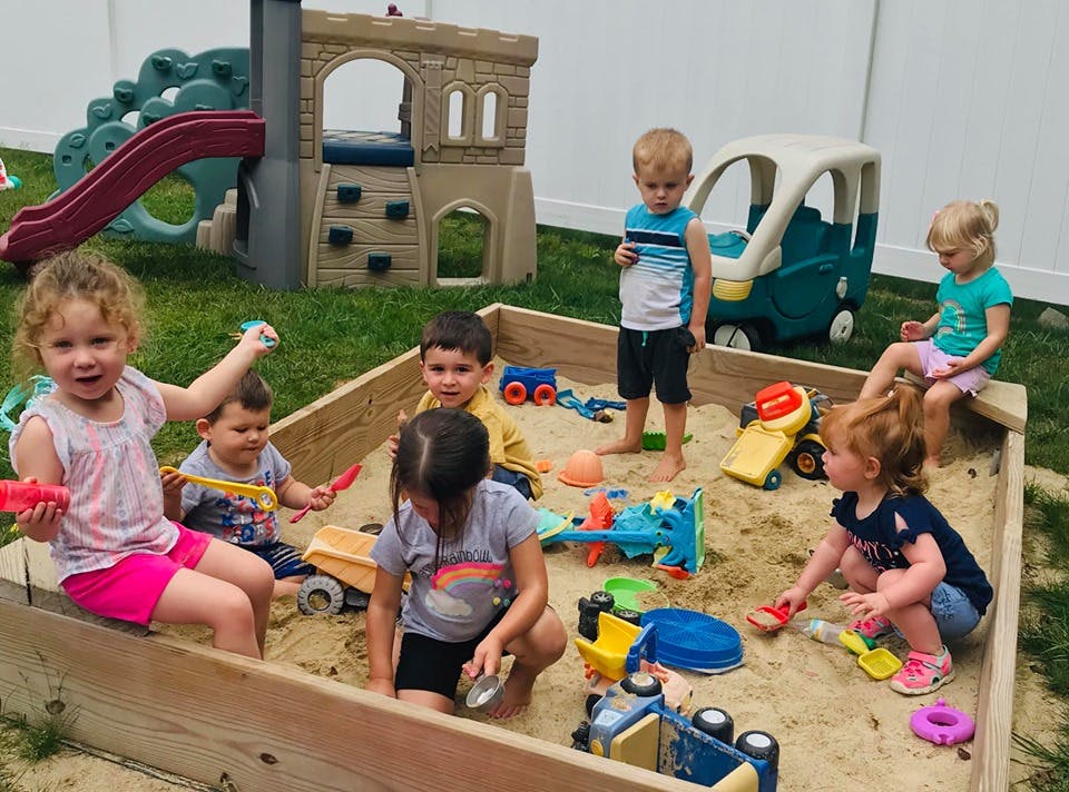 Children playing in a sandbox with toys