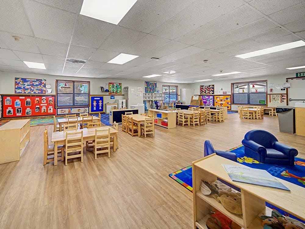 Empty classroom with small tables, chairs, and learning materials