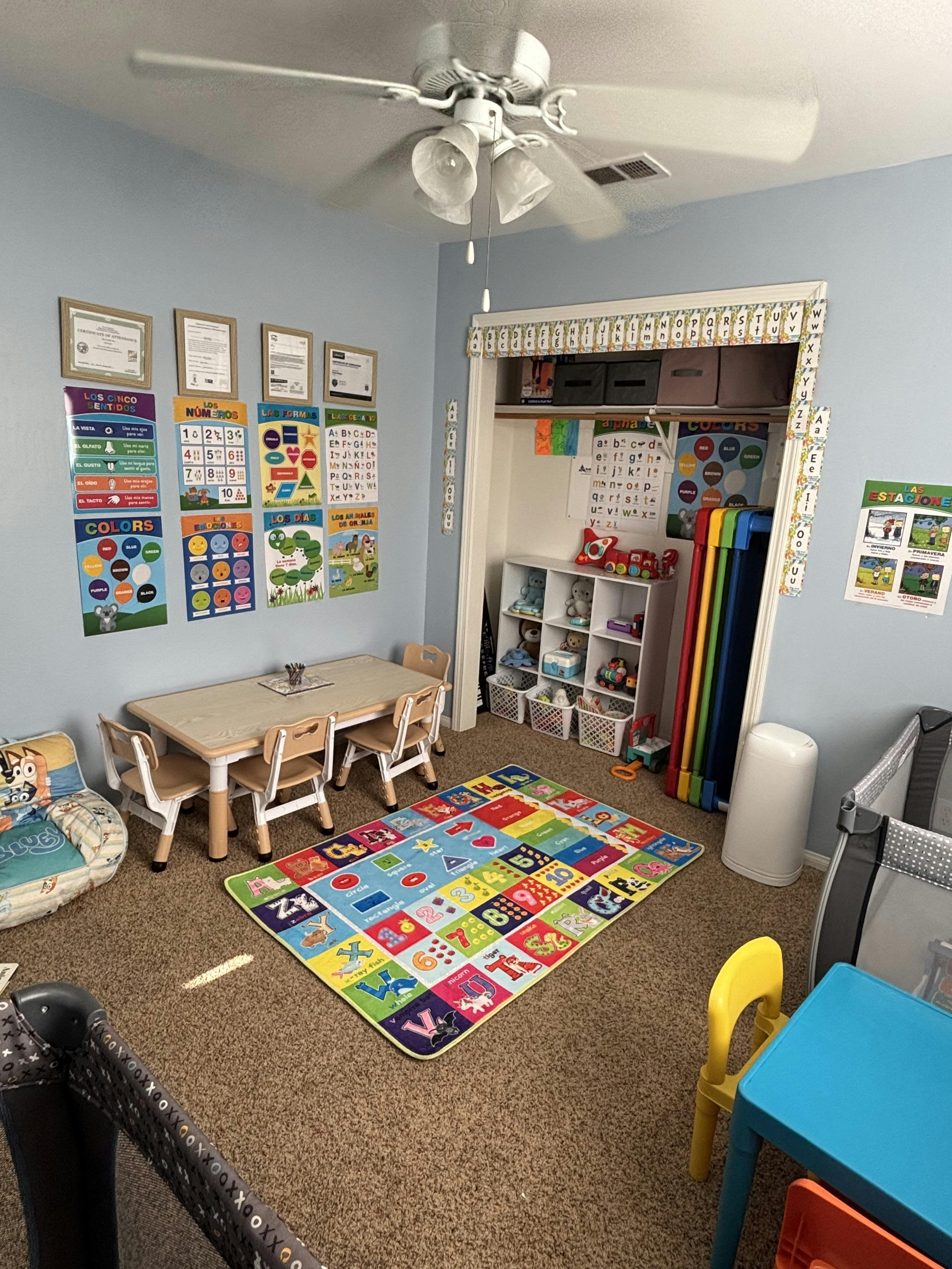 children's playroom with small table and chairs, colorful rug, crib, and learning posters