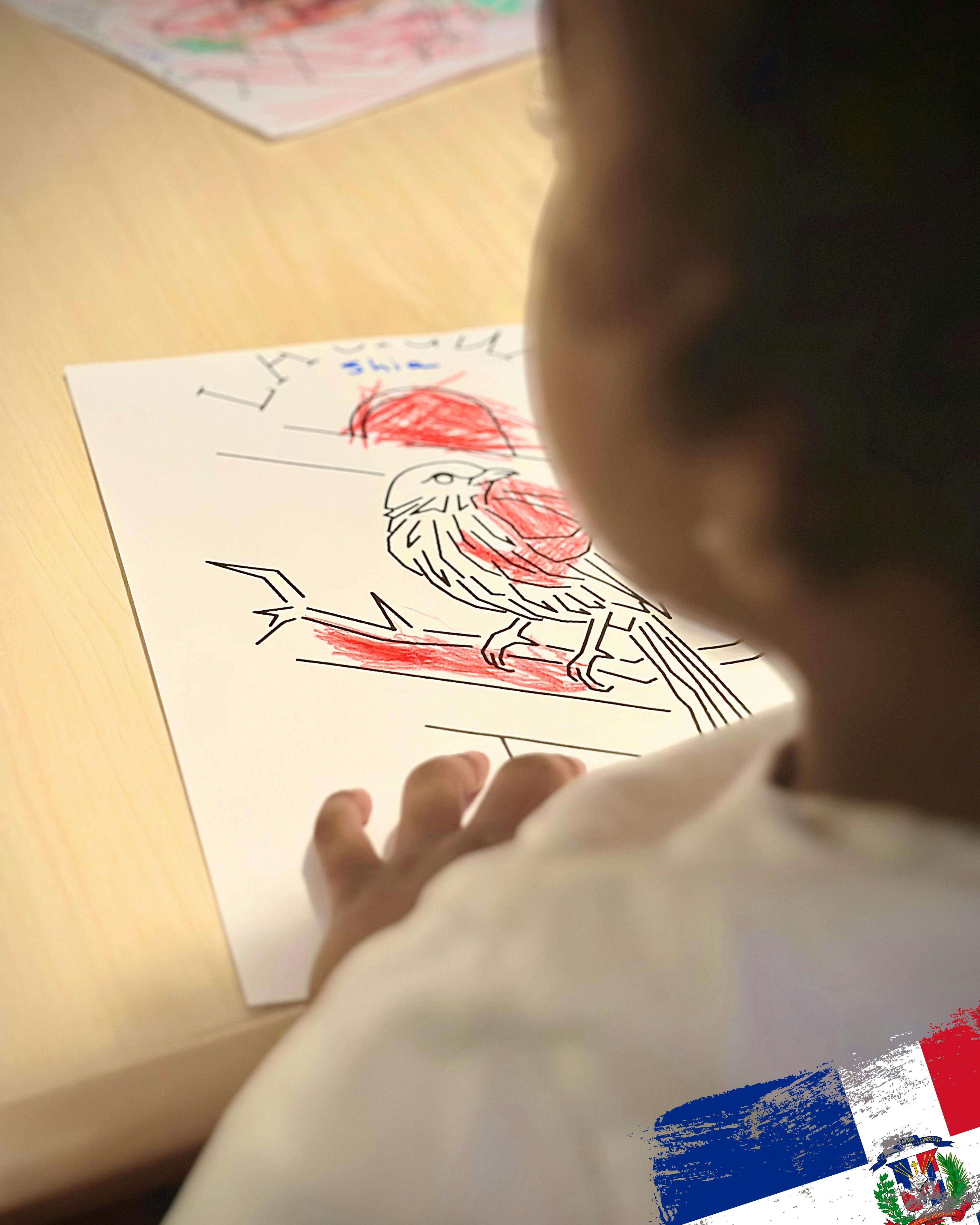 Child coloring a bird drawing with red crayon
