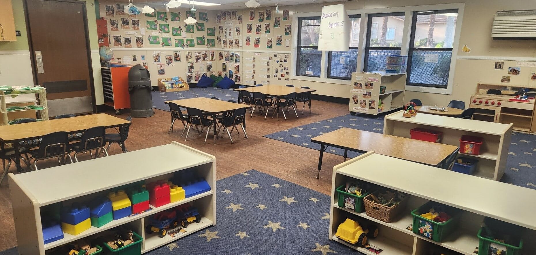 Empty colorful classroom with small tables, chairs, and play areas