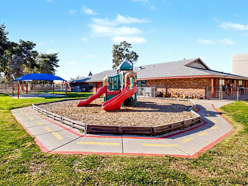 A playground with a slide structure and a small track on a sunny day