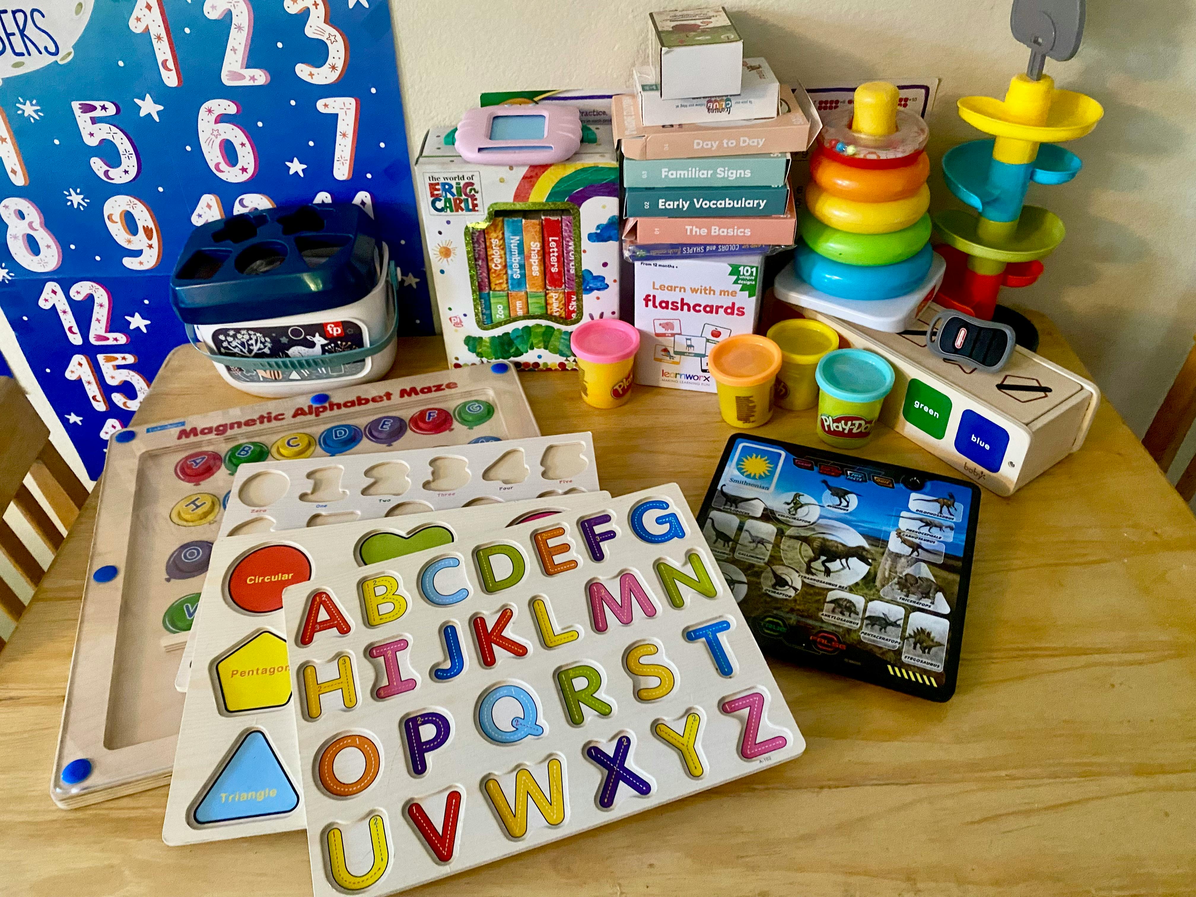 Table with various educational toys including alphabet puzzles and stacking rings