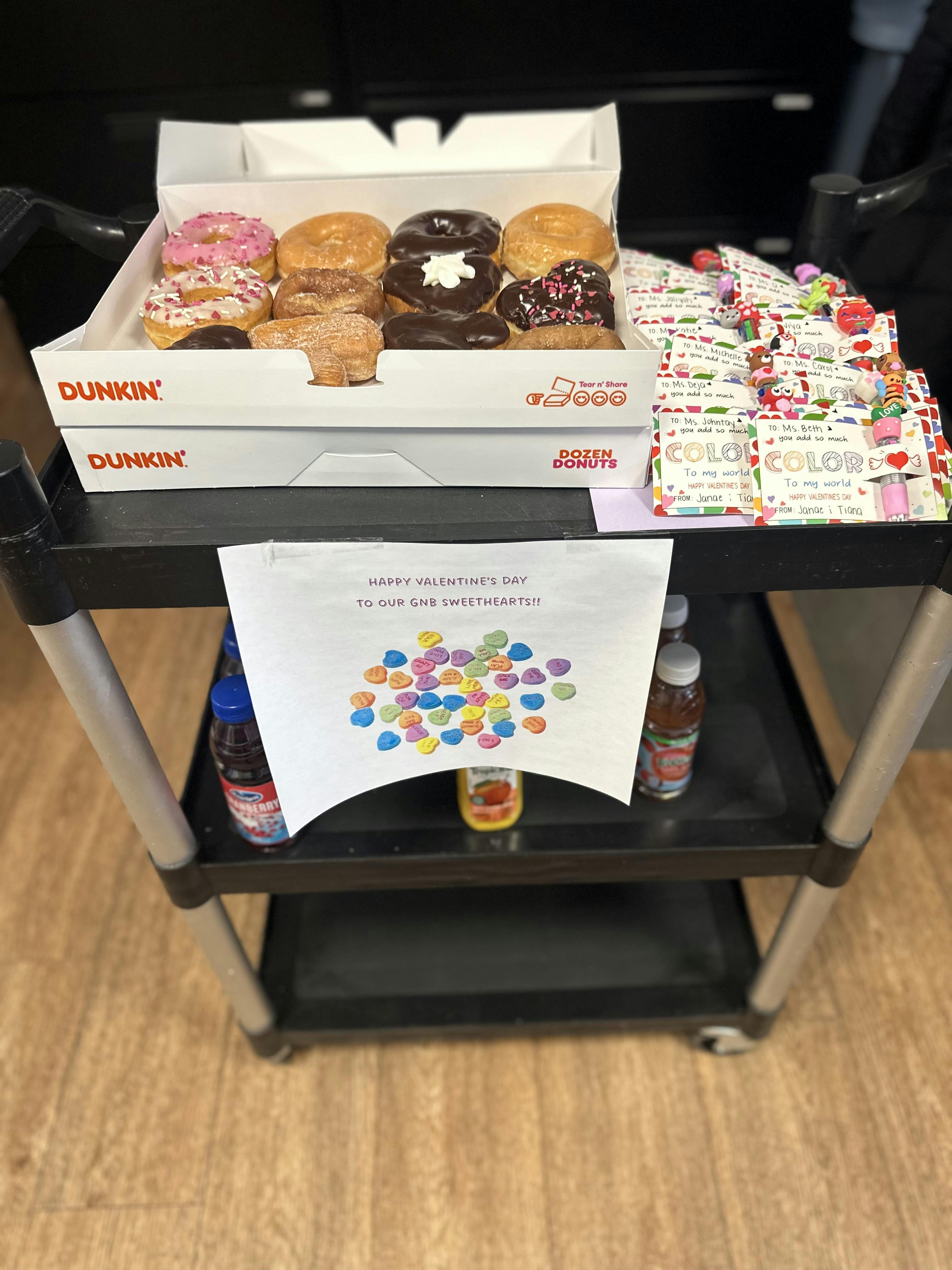 Dunkin' boxes of donuts and Valentine's Day cards on a black cart