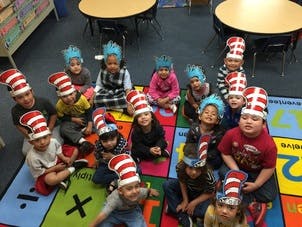 Children wearing hats sitting on a colorful rug