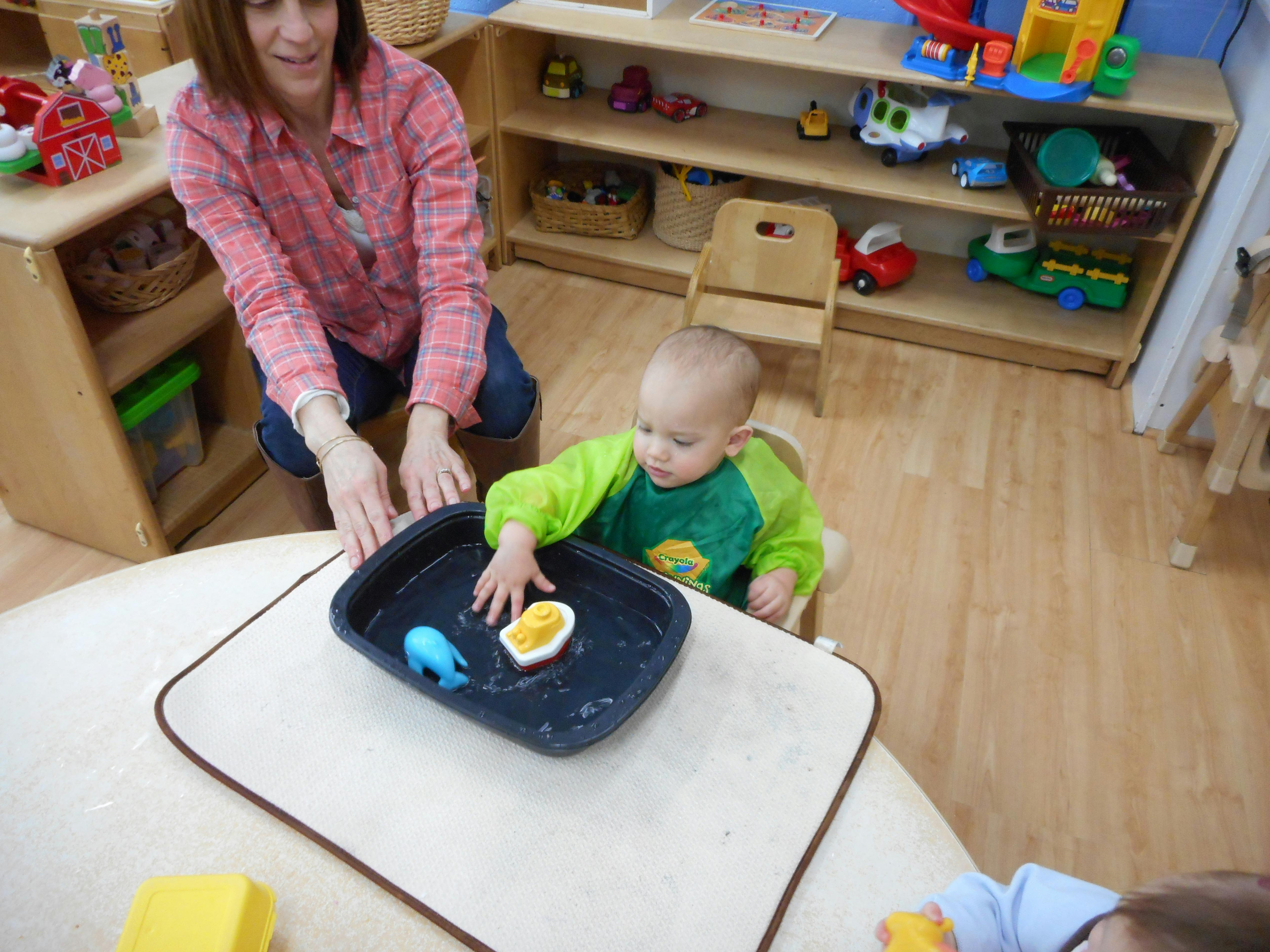 Adult and child playing with water and toys in a tray