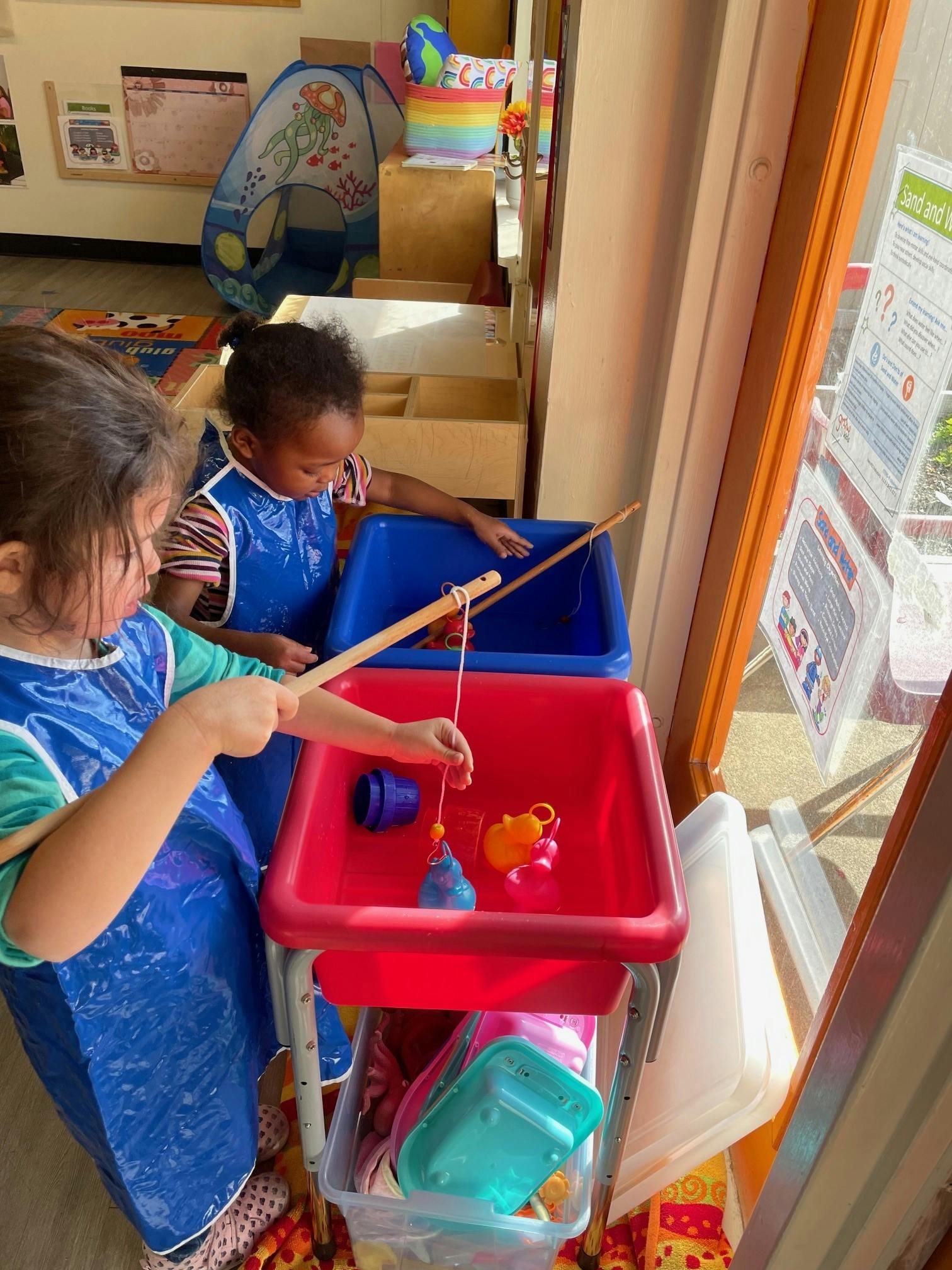 Two children playing with toy fishing rods in bins