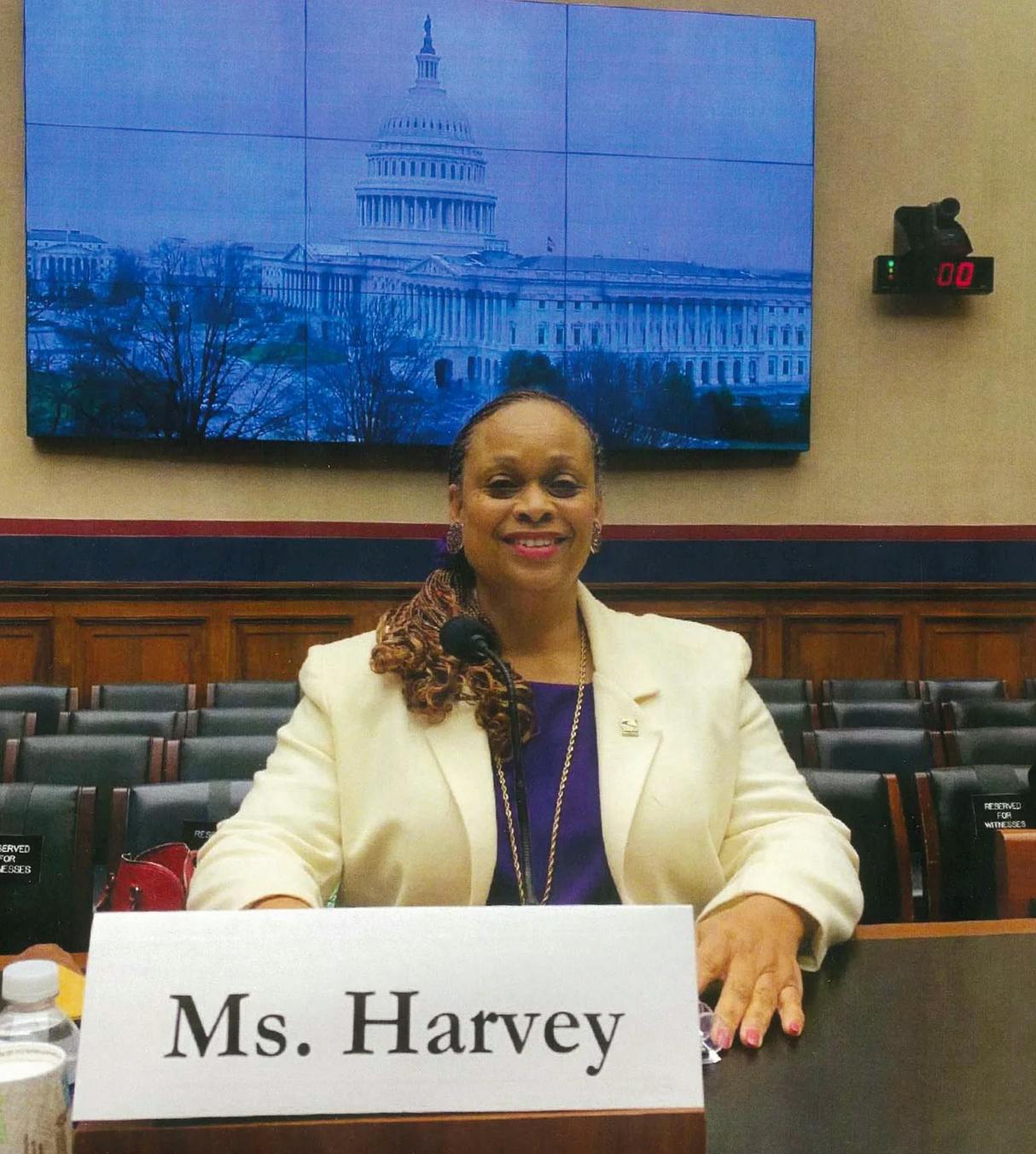 A person sitting at a desk with a name card reading Ms. Harvey
