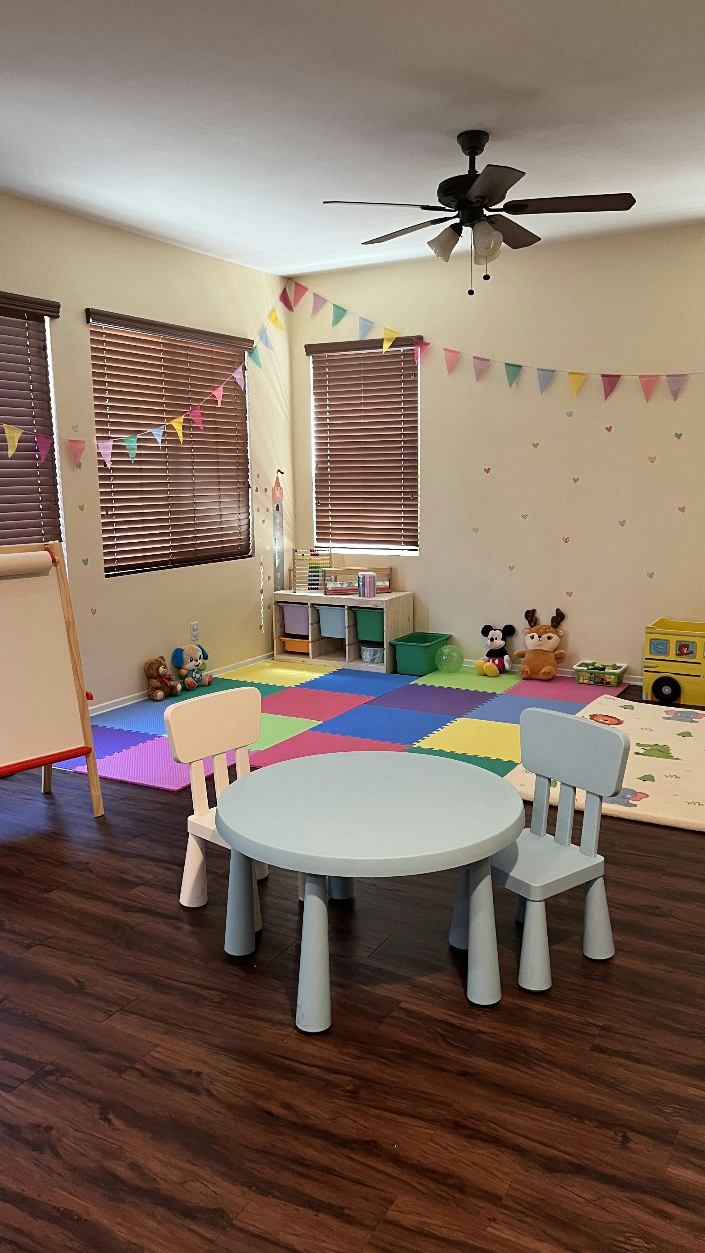 A children's playroom with a table and chairs on a colorful mat