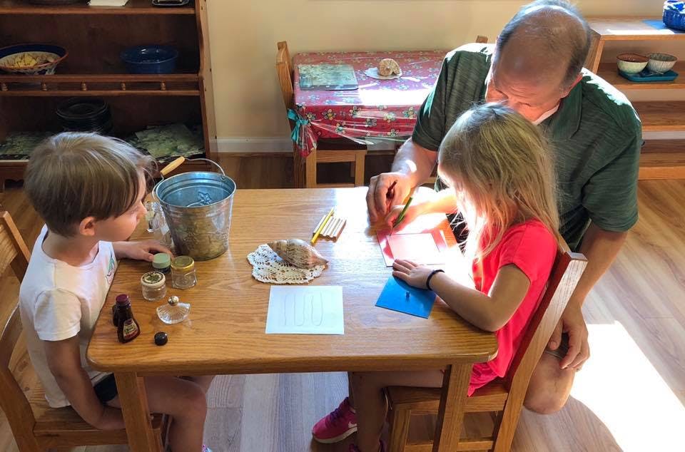 Adult and two children at a table with craft supplies