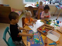 Three children playing with crafts at a table in a classroom
