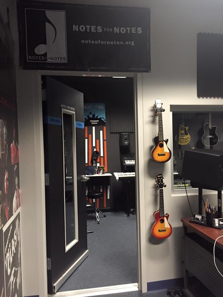 Music studio entrance with sign "Notes for Notes" and two ukuleles on wall