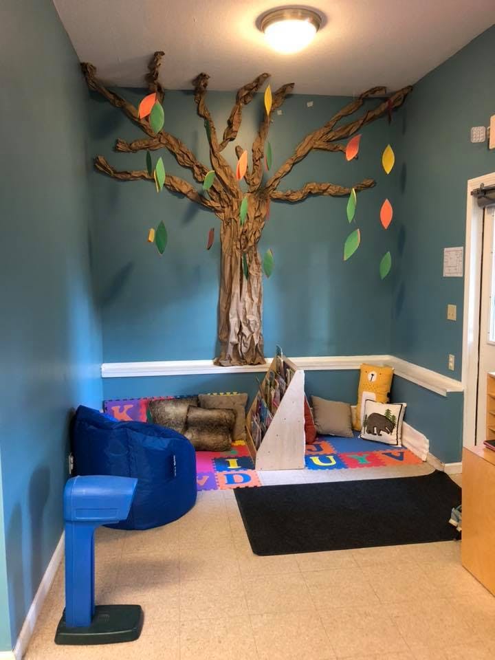 Reading nook with a tree mural, beanbag chair, and alphabet mat