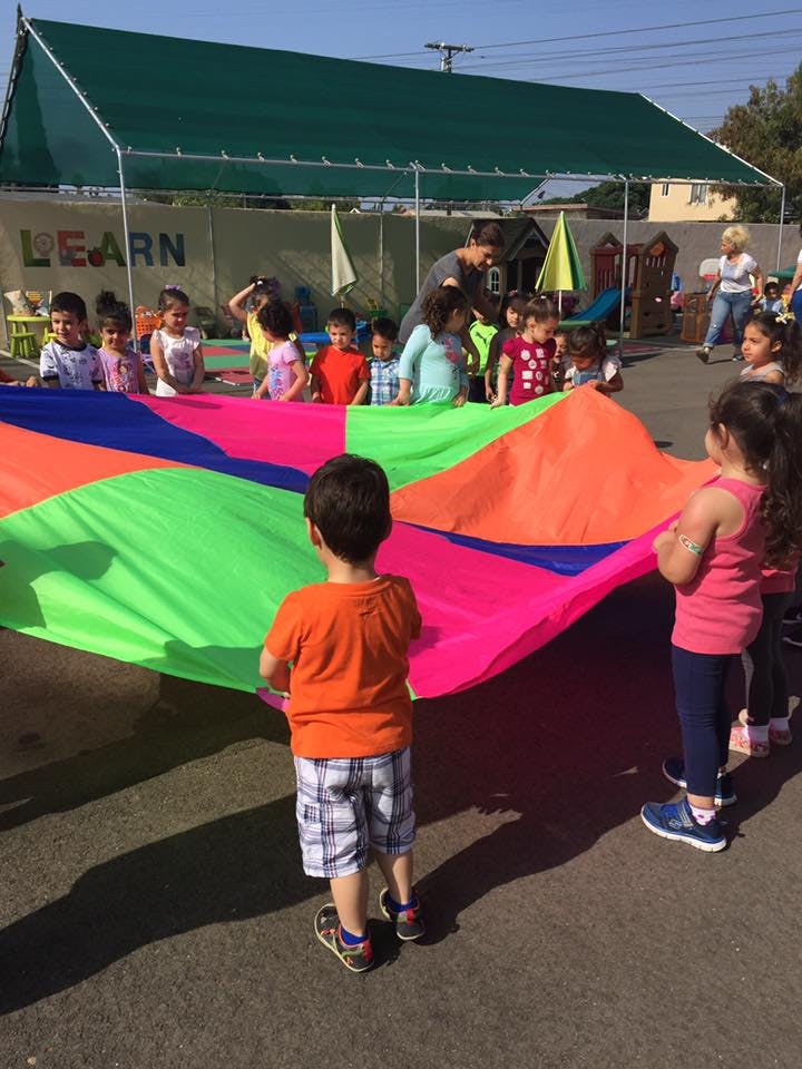 Children playing with a colorful parachute outdoors