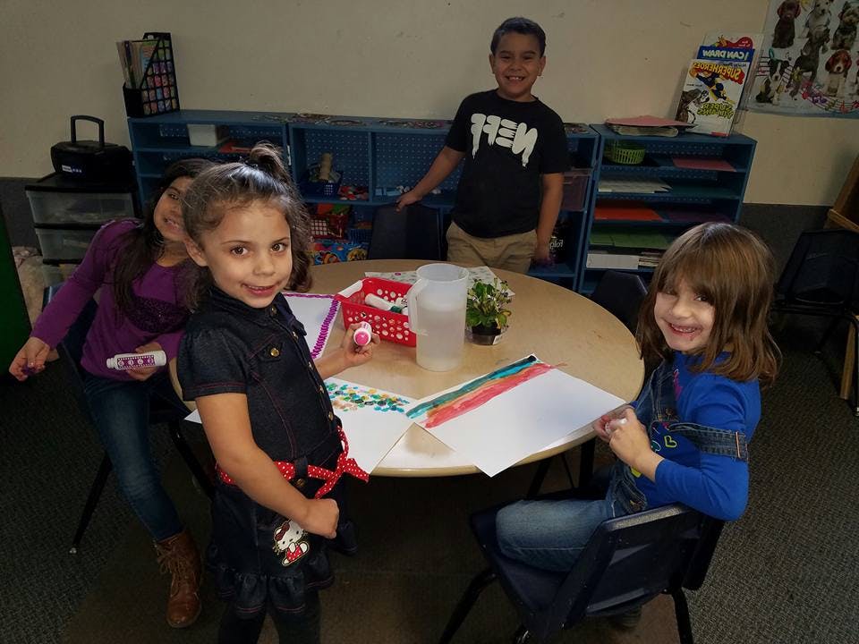 Three children around a table with papers
