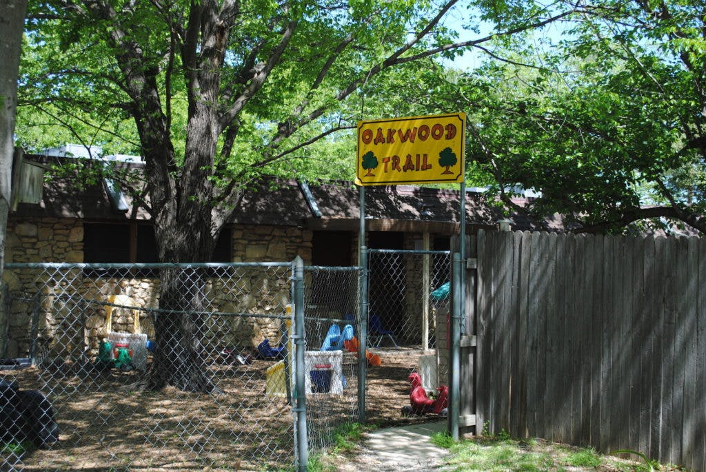 Yellow sign with "Oakwood Trail" above a chain link fence
