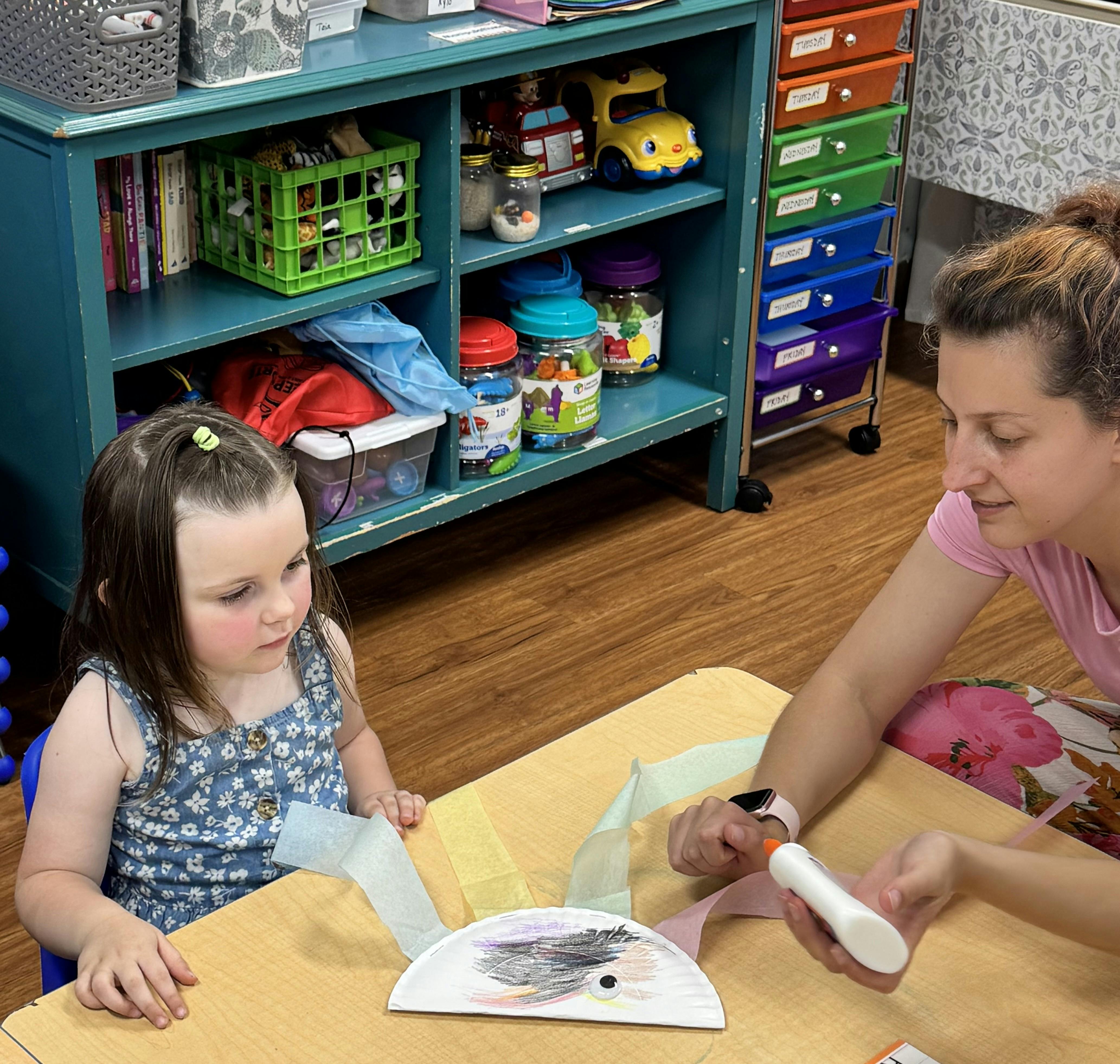 A person and a child working on a craft project together at a table