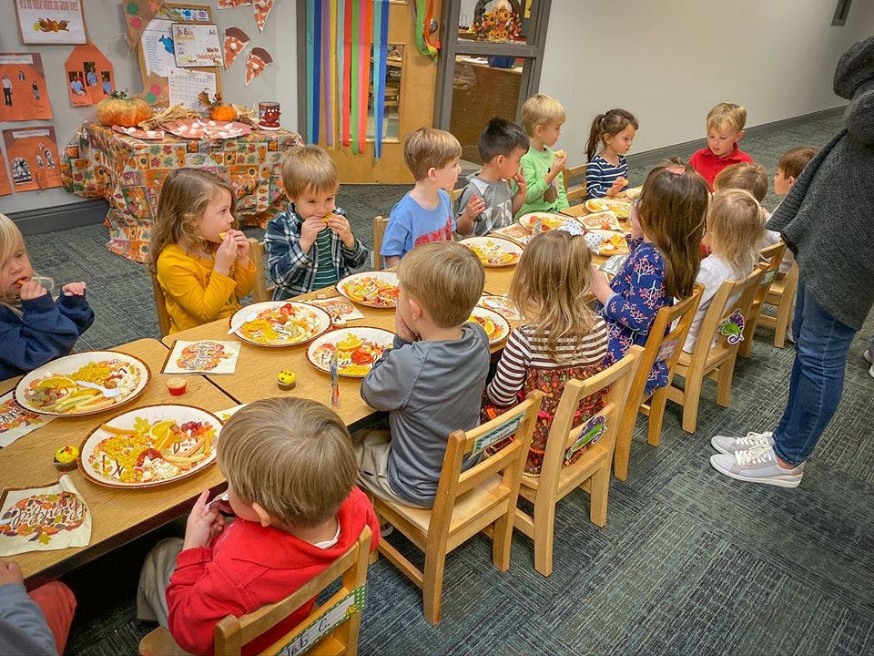 Children sitting at a long table with plates of food