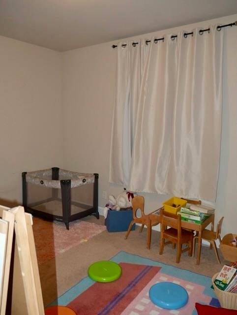 Playroom with a playpen, small wooden table, and chairs on a rug