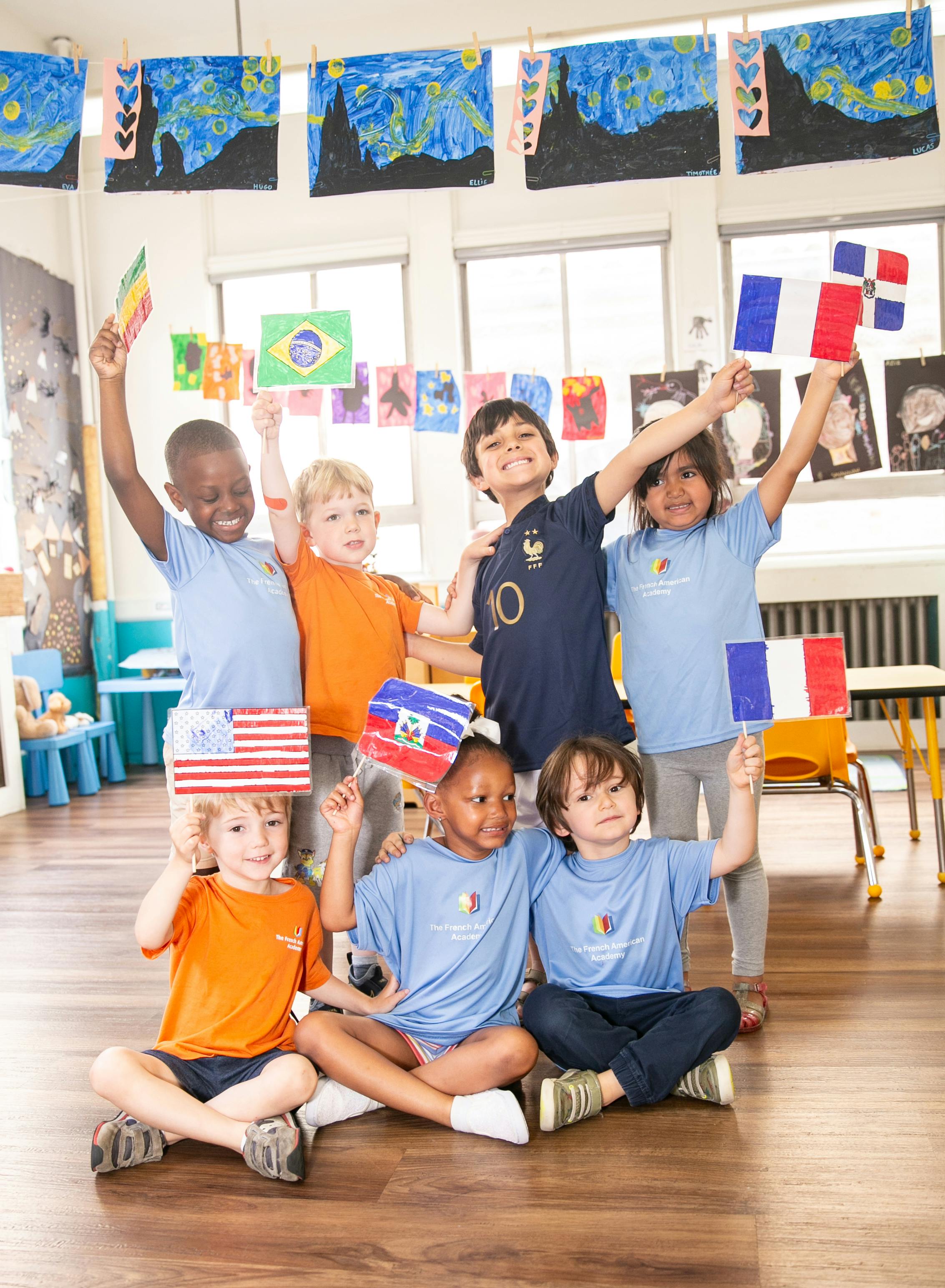 Group of children holding up various national flags in a classroom