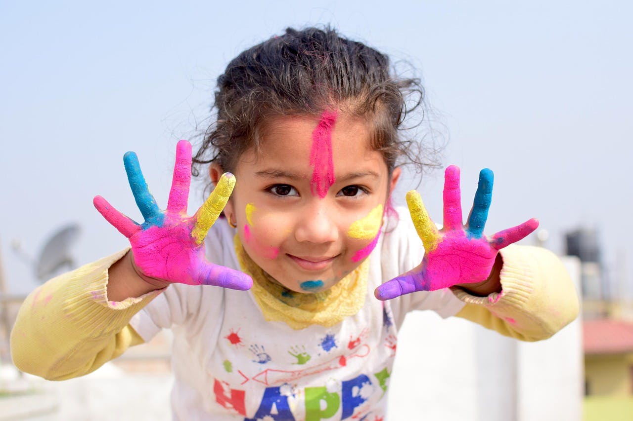 Child with colorful paint on face and hands