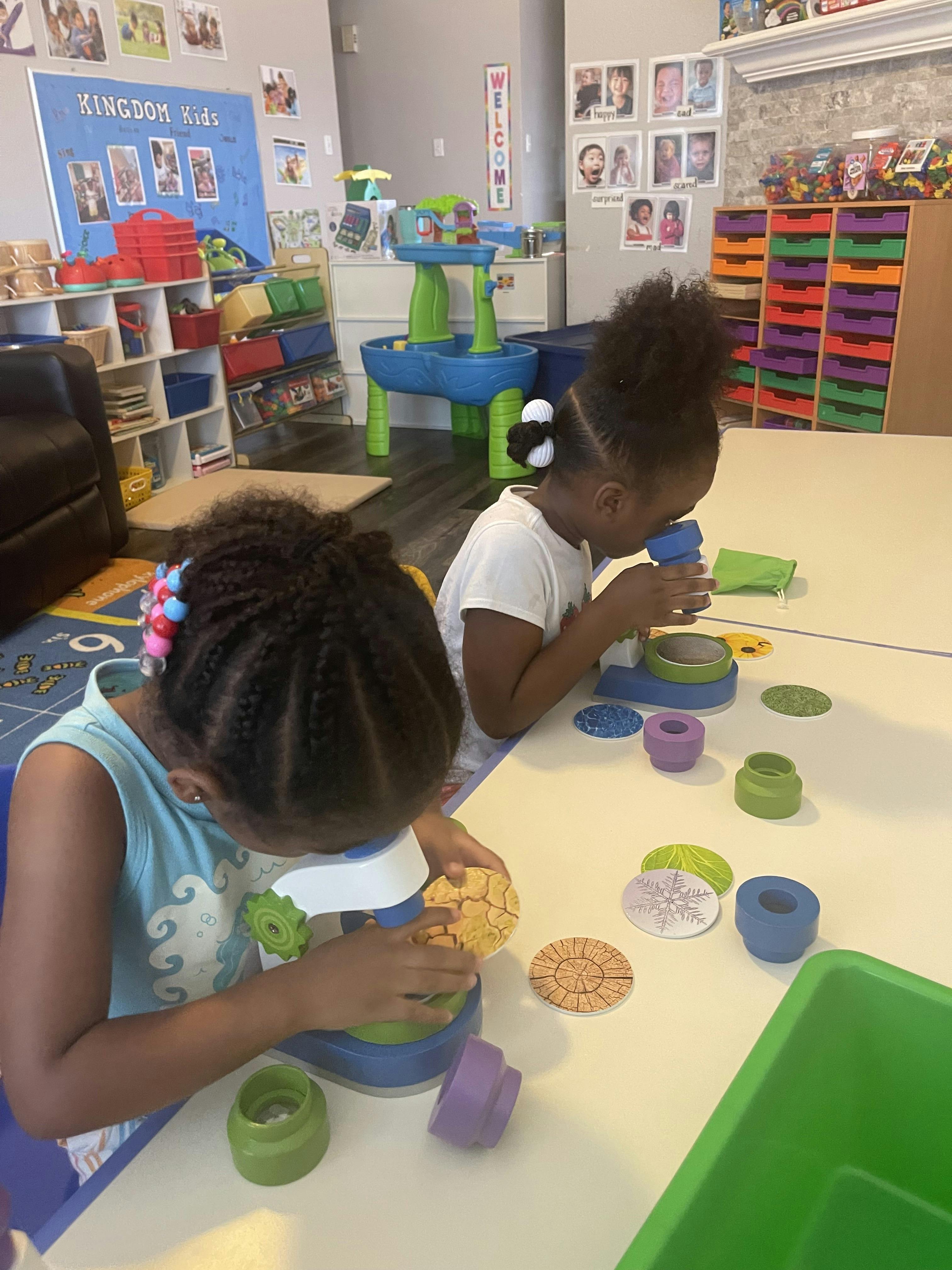 Two children using toy microscopes in a classroom
