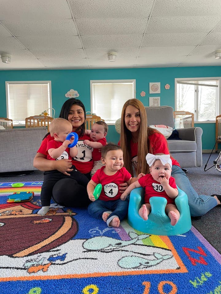 Two people with four babies in a room with cribs