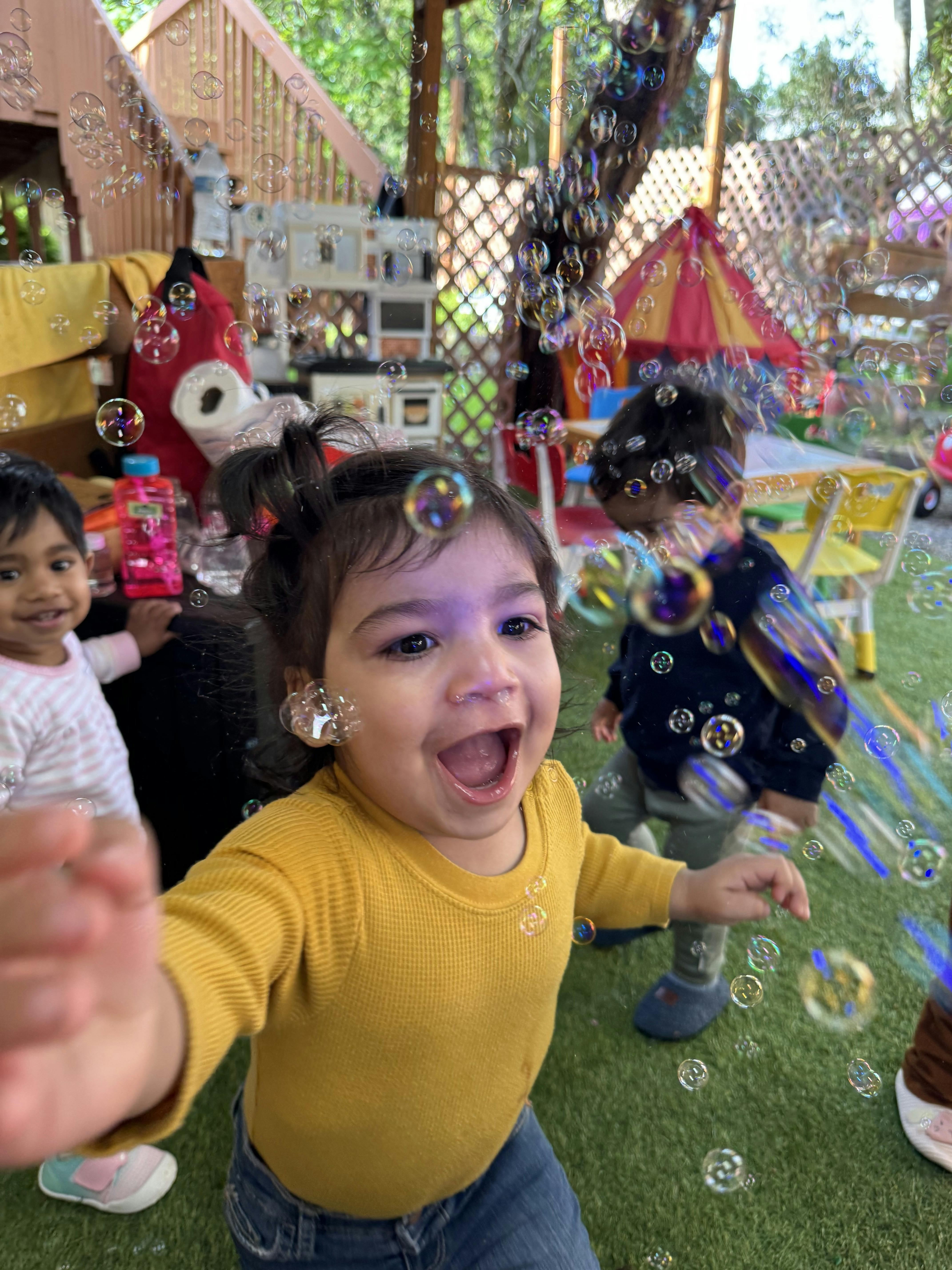Laughing child reaching towards the camera among bubbles