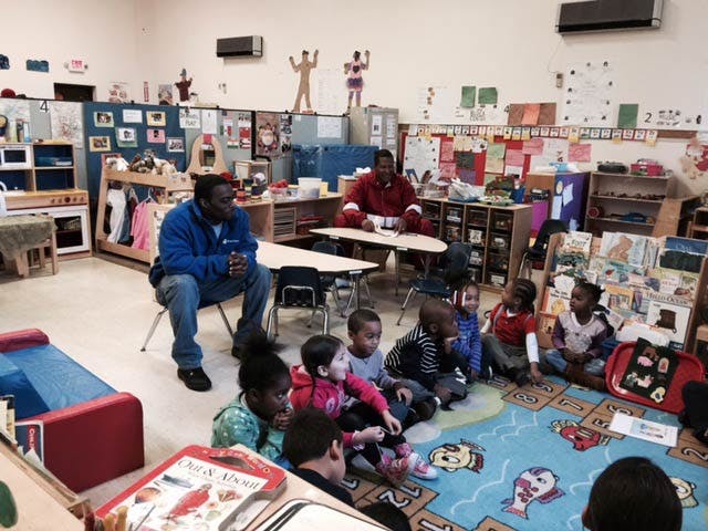 Adults and children sitting on the floor in a classroom