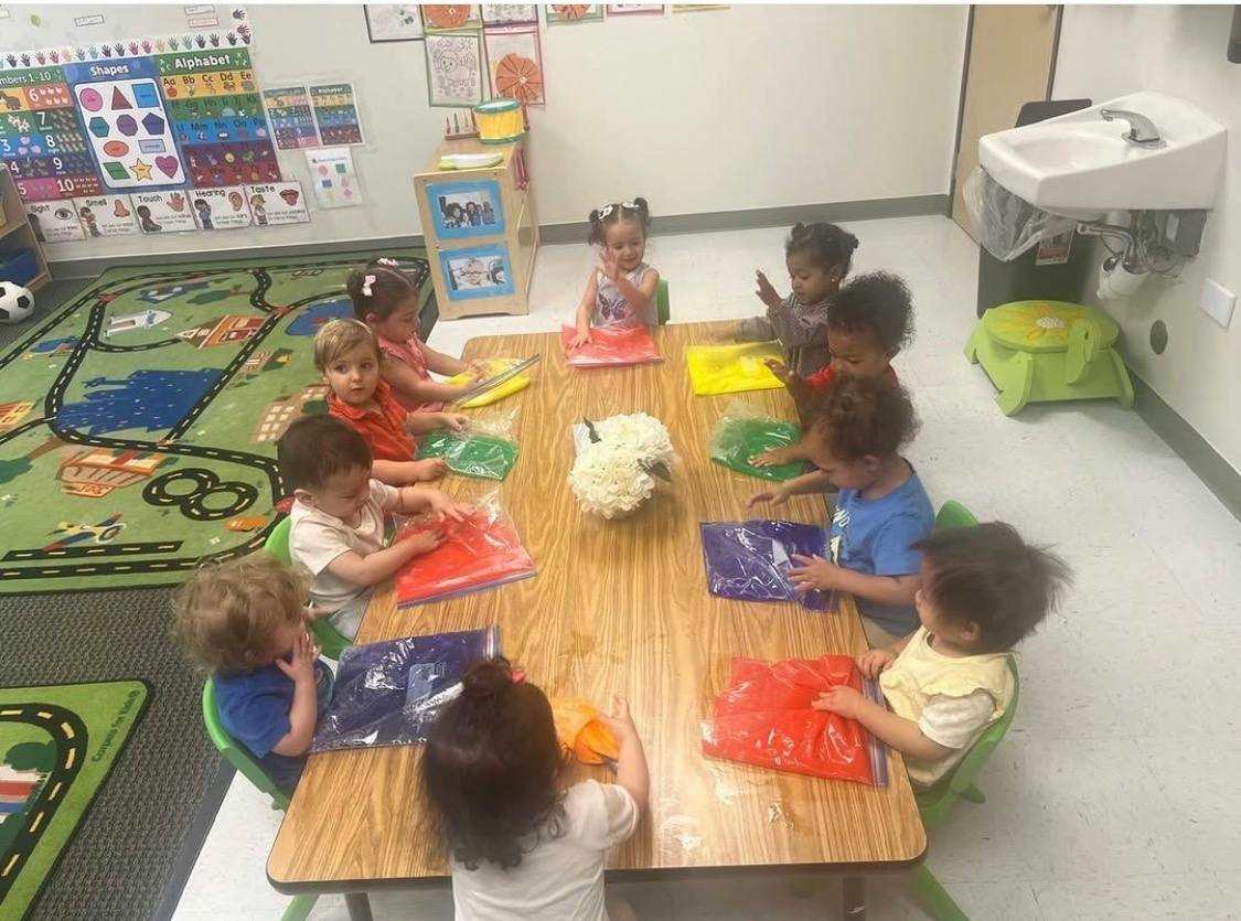 Group of children playing with sensory bags at a table in a classroom
