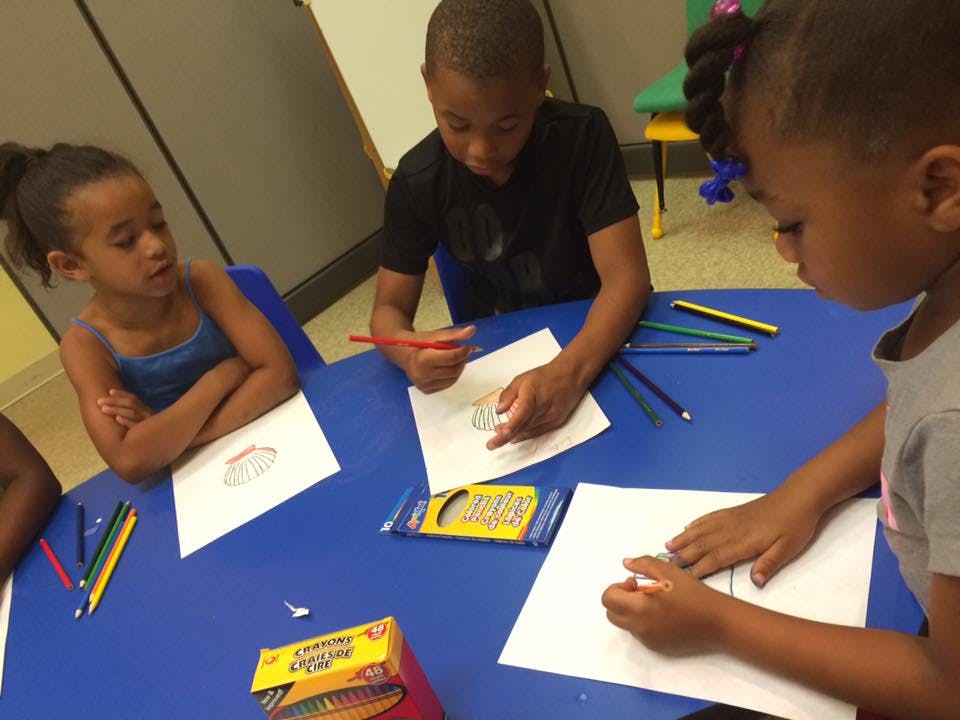 Three children drawing at a table