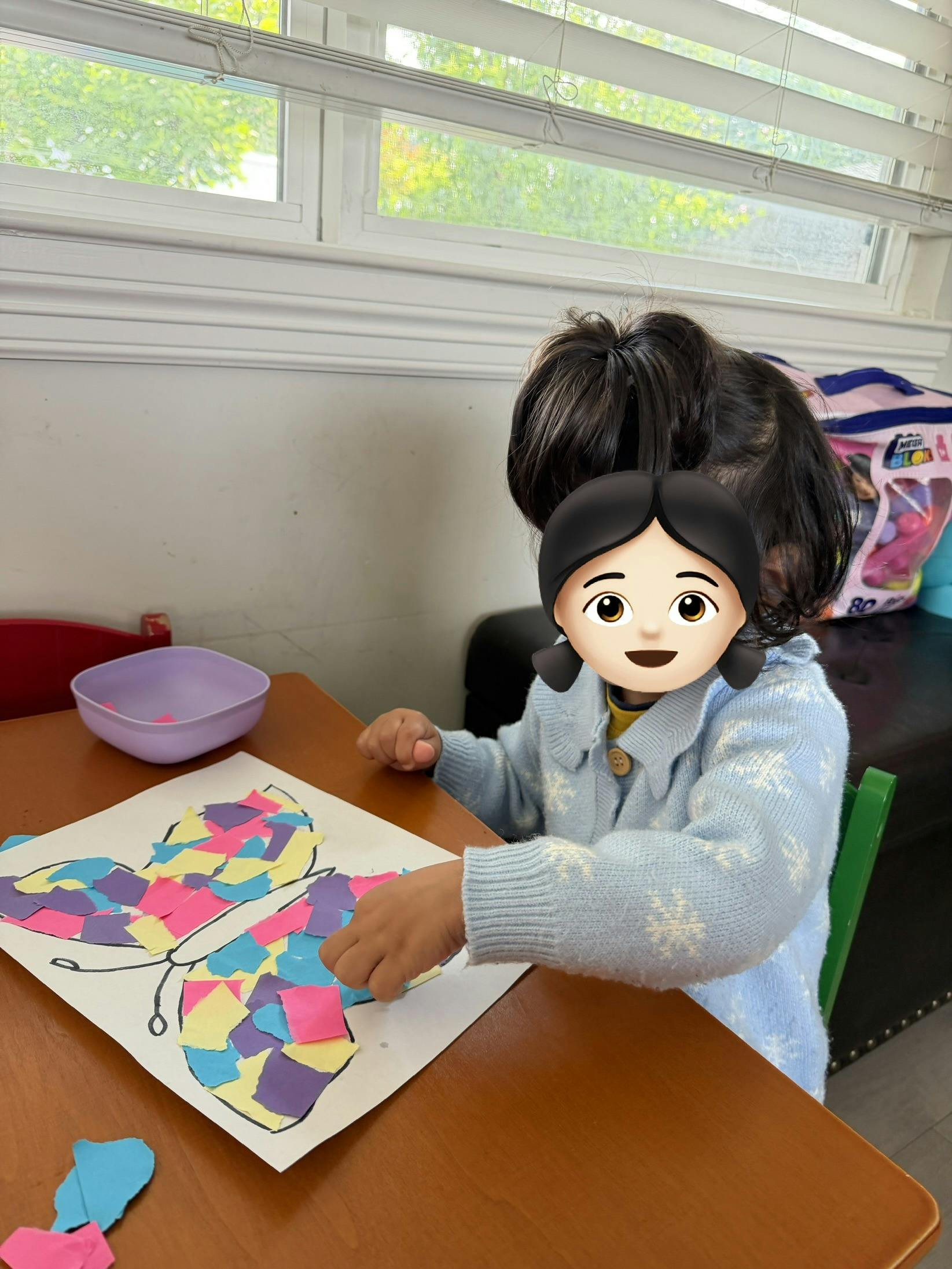 Child doing a butterfly craft with colorful paper pieces