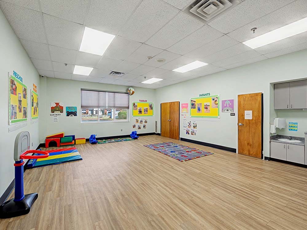 Empty classroom with light green walls and wood-look flooring