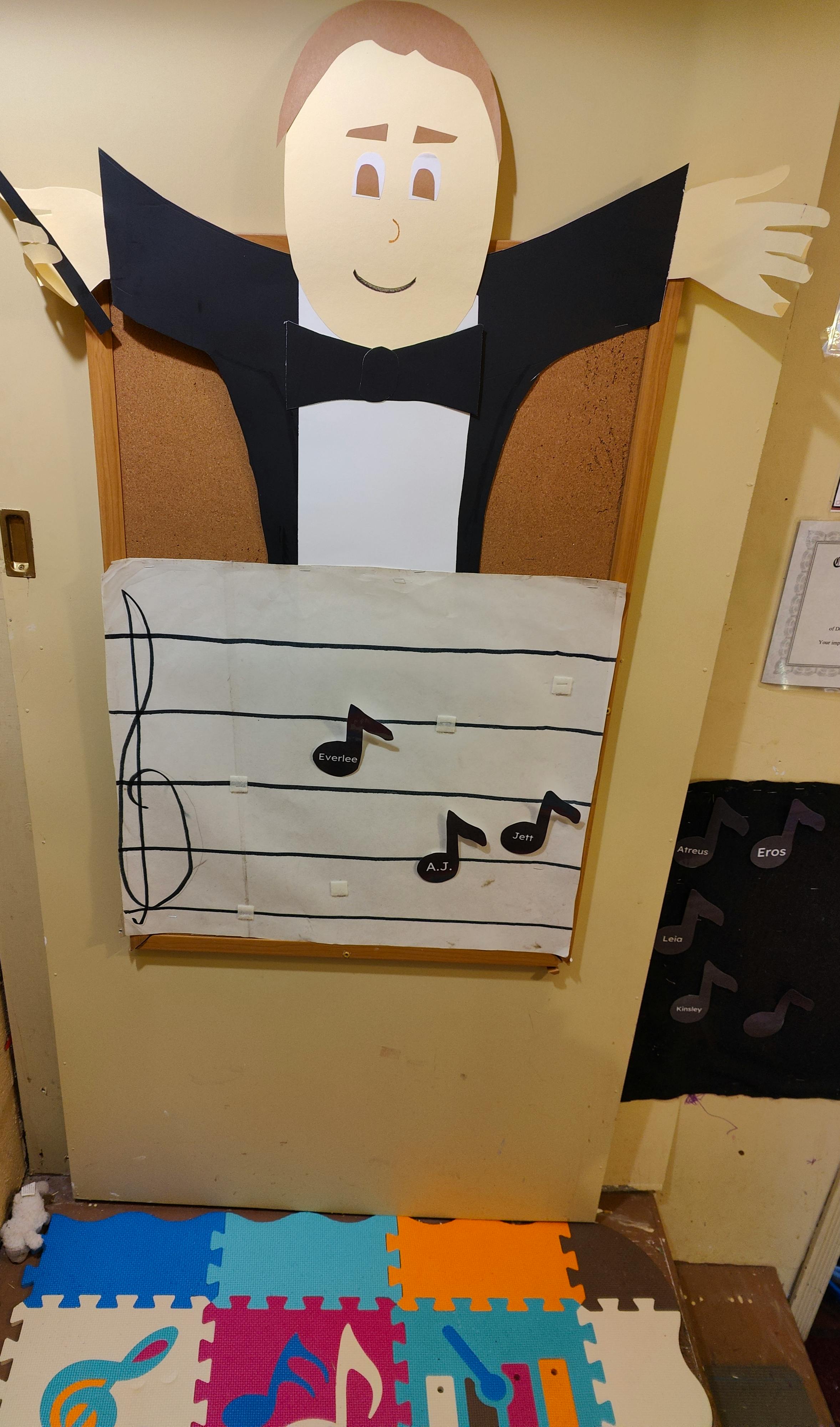 Paper cutout of a conductor with a music sheet and notes below