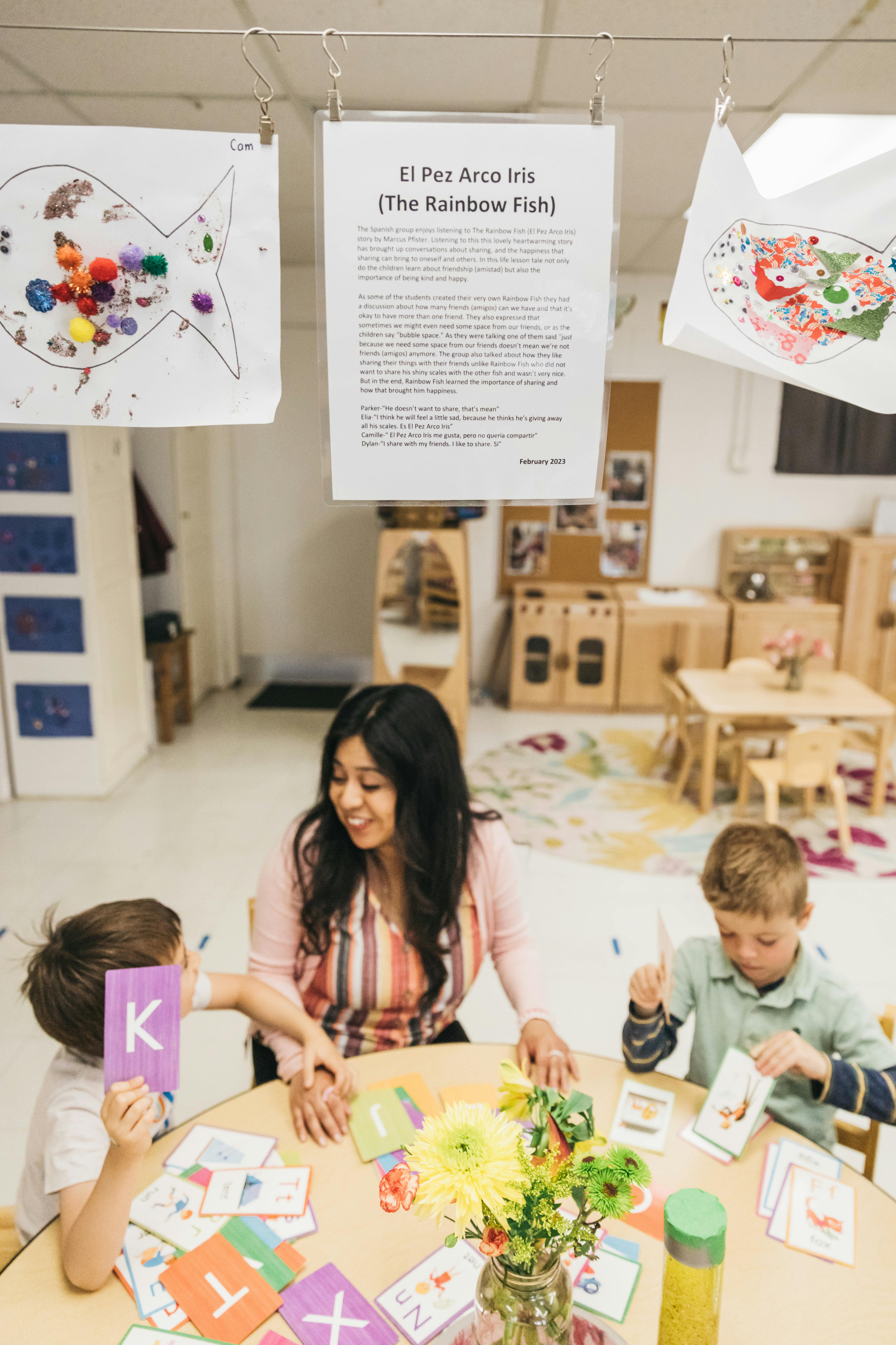 Adult and two children at a table with alphabet cards and flowers