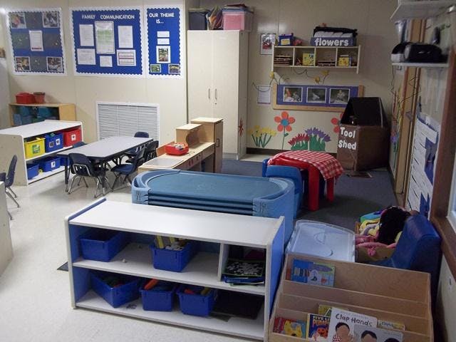 A colorful classroom with tables, chairs, storage shelves, and play areas