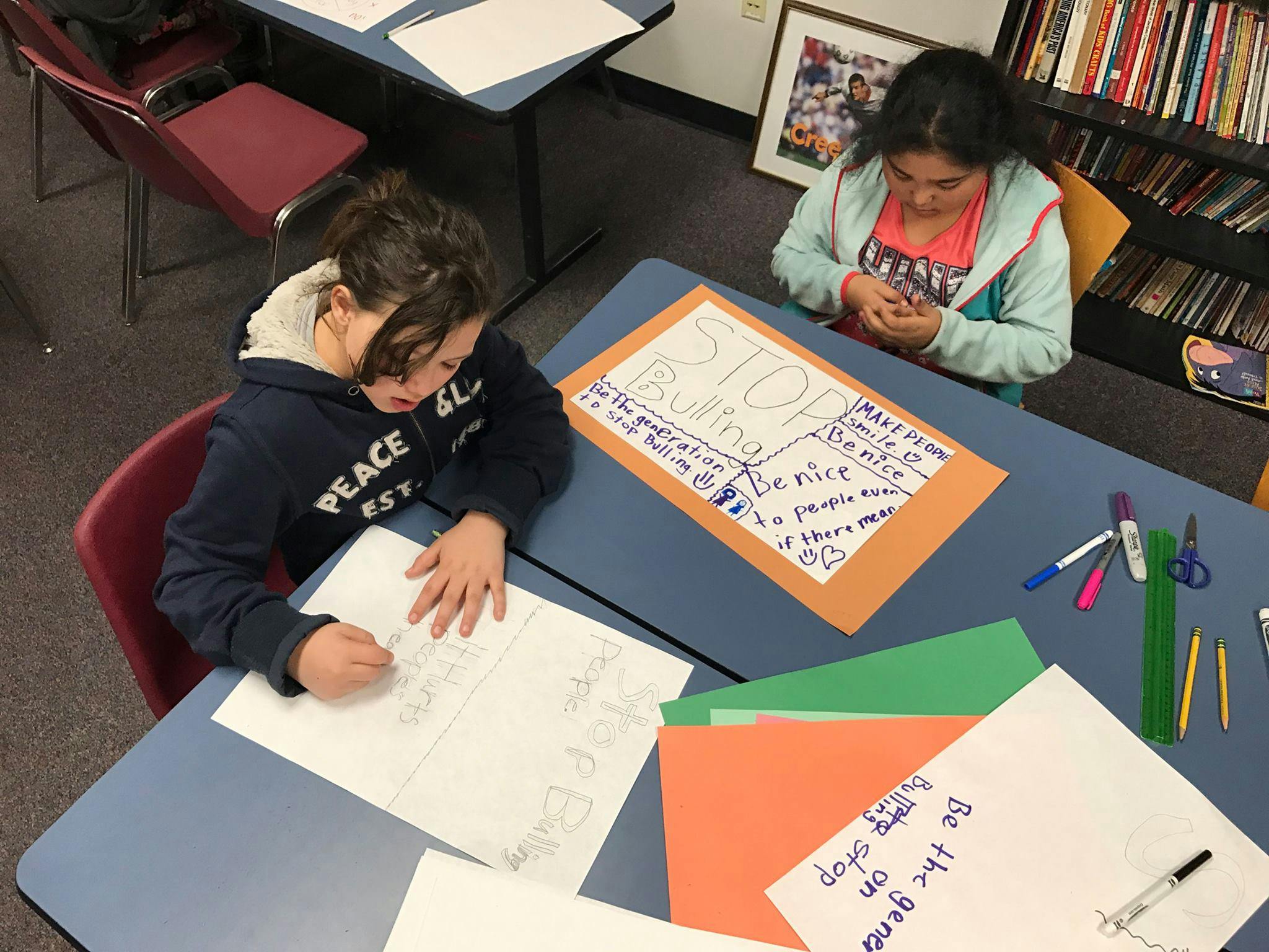 Two children working at desks in a classroom