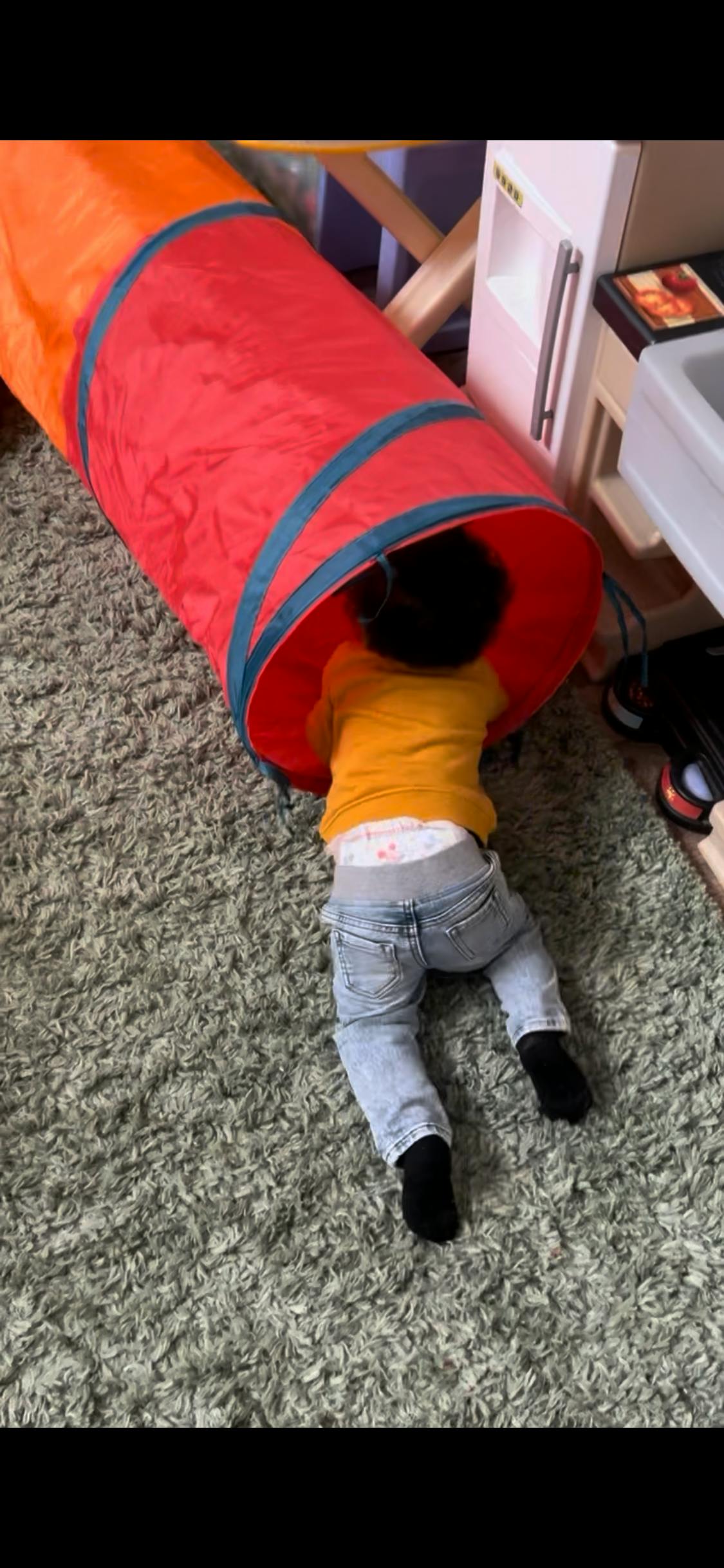 Child crawling into a fabric play tunnel