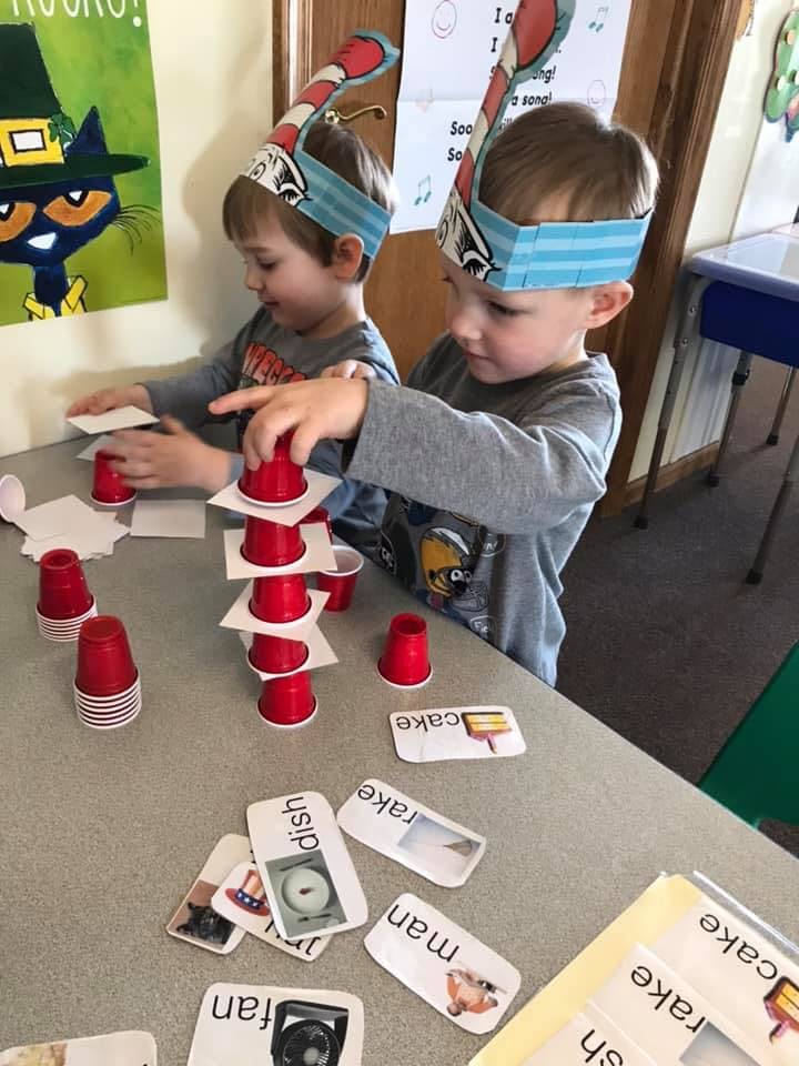 Two children building towers with red cups and paper squares