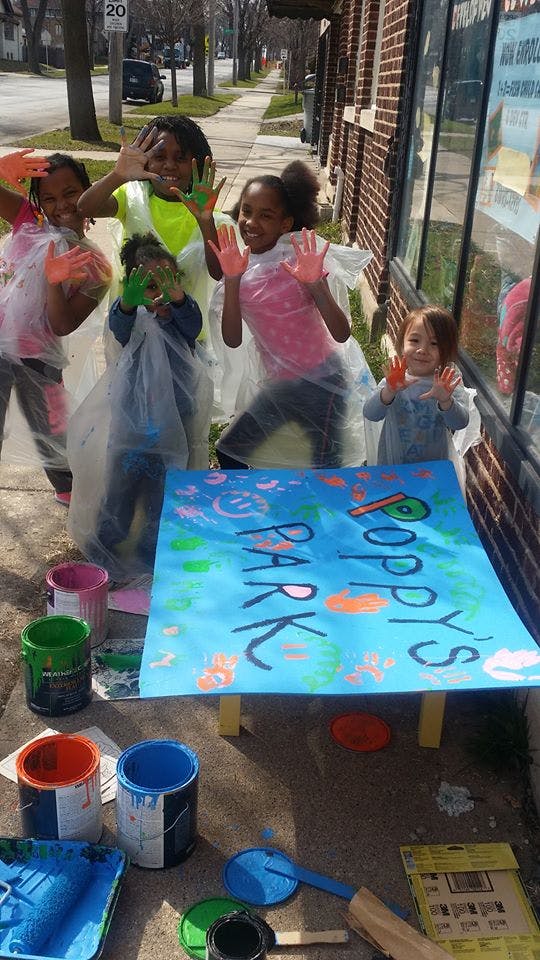 Children with paint on their hands standing around a painted sign