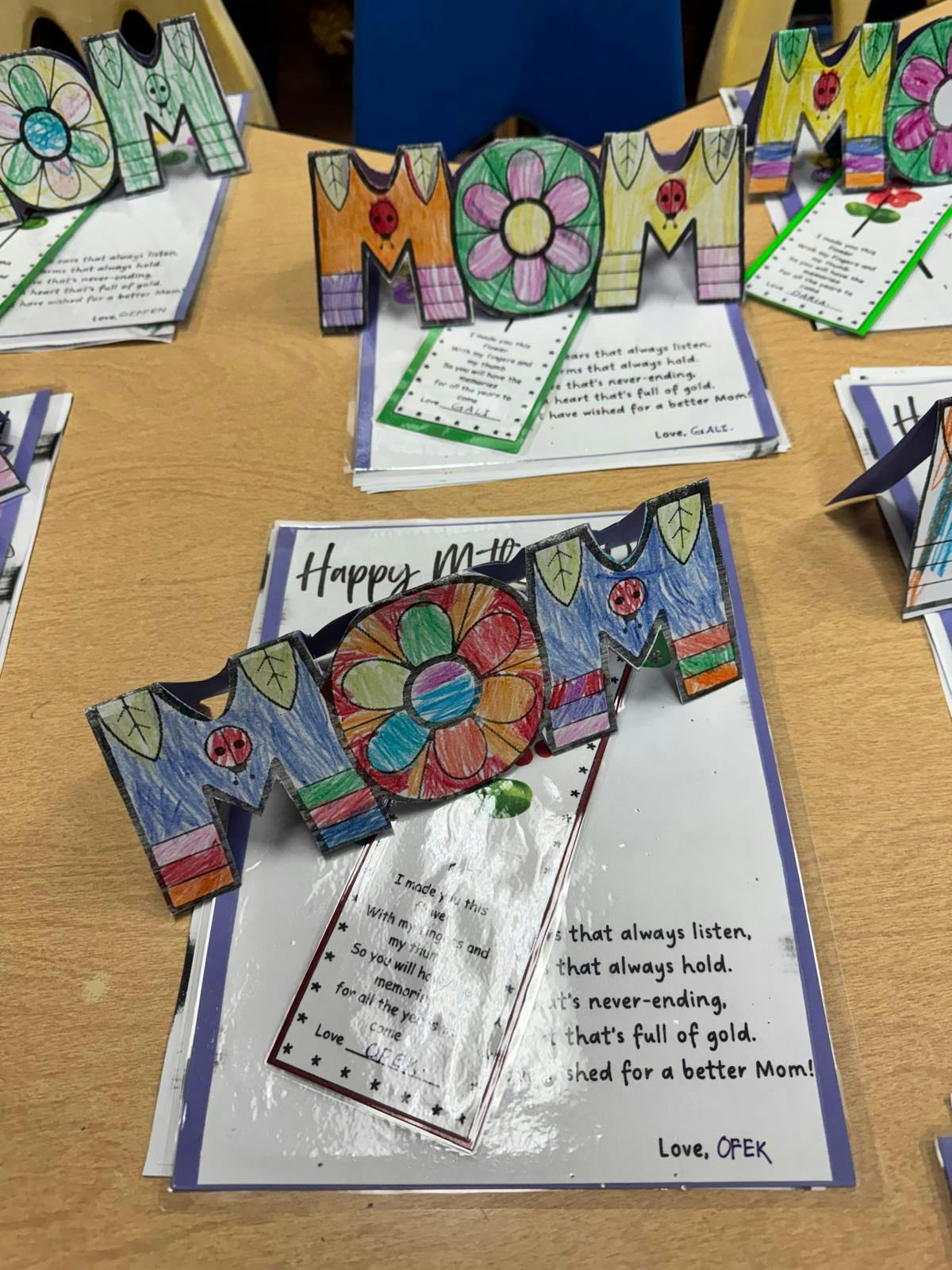 Multiple handmade cards with "MOM" cutouts and text, including "Happy Mom"