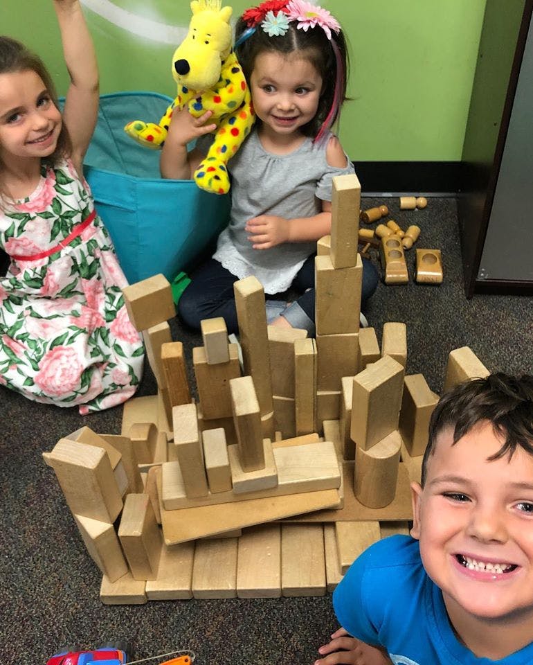 Three children playing with wooden blocks
