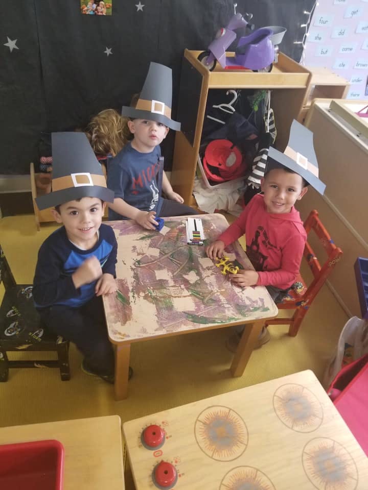 Three children wearing pilgrim hats sitting at a table